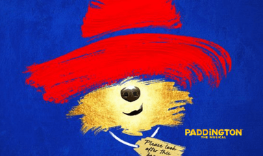 Illustrated promotional artwork for Paddington The Musical featuring Paddington Bear’s red hat, golden fur, black nose, and iconic ‘please look after this bear’ tag, set against a bright blue background with yellow title text.