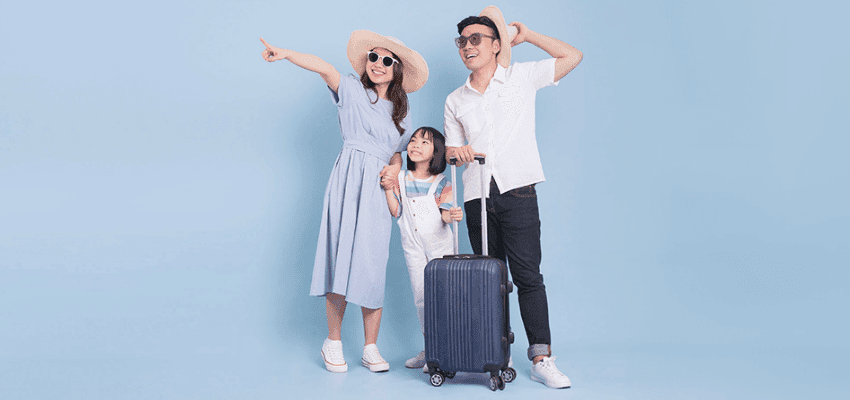 A cheerful family of three dressed for a holiday, standing with their luggage against a light blue background, representing secure and carefree travels. 