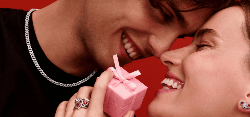 Couple smiling and holding pink gift box with Pandora jewellery promoting Valentine gift ideas with disabled discounts in the UK