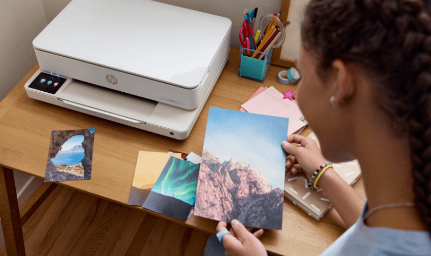 Young woman printing travel photos with an HP printer from Currys. Save on tech essentials with exclusive disabled student and home office discounts UK-wide
