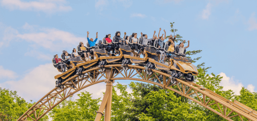 Group of thrill-seekers on a rollercoaster at Thorpe Park, raising their hands in excitement against a clear blue sky. Promotes Purpl’s Thorpe Park disabled discounts, including accessibility passes, companion ticket offers, and mobility-friendly theme park experiences.