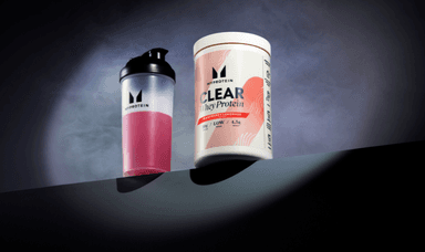 MyProtein shaker with pink liquid and Clear Whey Protein tub in Raspberry Lemonade, set against a smoky backdrop. Includes Shopping Discounts for Disabled People and Mobility Discounts.