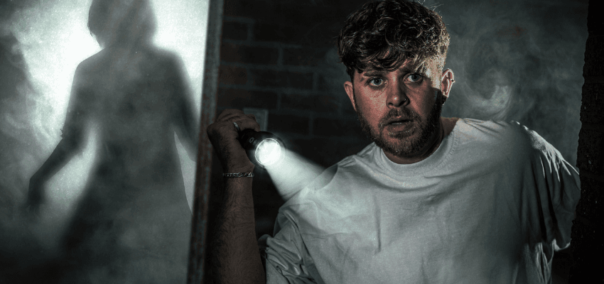 Frightened man shines torch beside shadowy figure at Thorpe Park—Purpl discounts for disabilities and long term health conditions, disabled travel discounts UK.