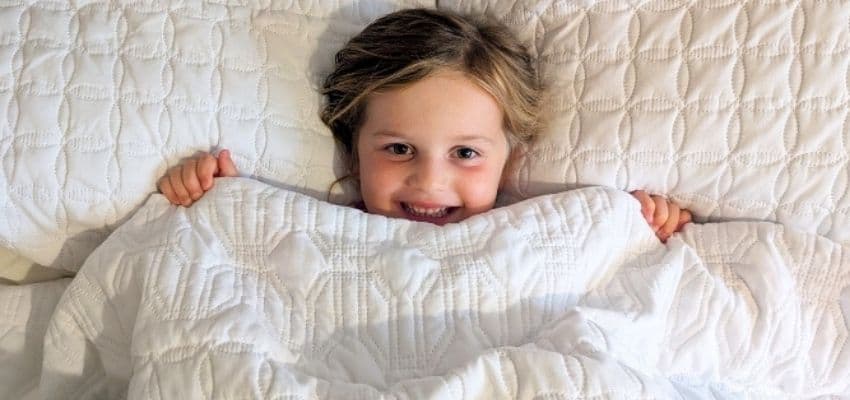 Smiling child under quilt, Sleepy Piglet: Purpl discounts for disabilities and long term health conditions, shopping discounts for disabled people.
