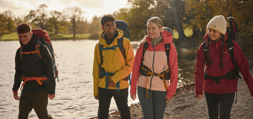 Group in Craghoppers waterproofs walking by a lake, promoting Craghoppers savings for disabled people and mobility needs.