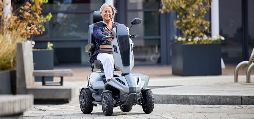Woman riding a powered mobility scooter outdoors, CareCo Purpl disability discounts members save on mobility scooters and daily living aids.