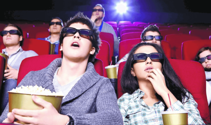 Group of friends laughing and watching a film in a modern cinema, with popcorn and drinks in hand, capturing the joy of shared entertainment and inclusive disabled cinema deals UK.