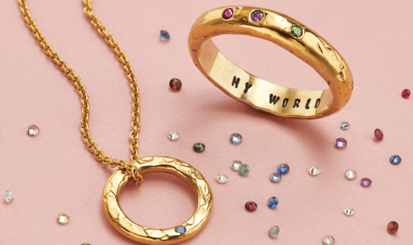 Gold ring engraved with My World and a matching circular pendant from Posh Totty, surrounded by scattered birthstone-style gems, perfect for meaningful jewellery gifts. Customisable Jewellery Offers for Disabled People.