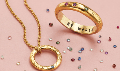 Gold ring engraved with My World and a matching circular pendant from Posh Totty, surrounded by scattered birthstone-style gems, perfect for meaningful jewellery gifts. Customisable Jewellery Offers for Disabled People.