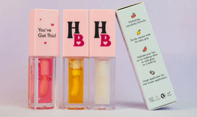 A trio of Human Beauty hydrating lip glosses in elegant square tubes with vibrant shades, promoting an eco-friendly and stylish makeup choice.