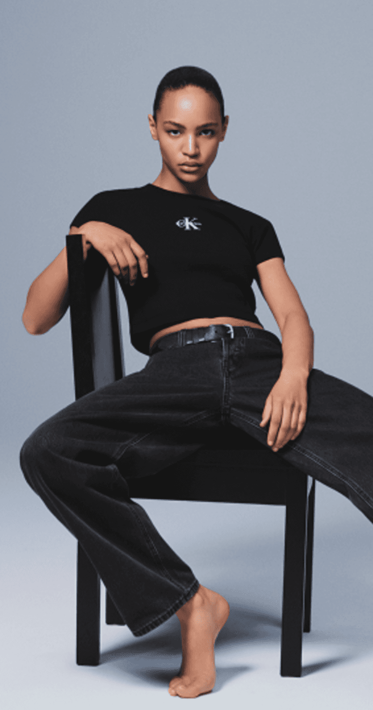 Woman in black Calvin Klein t-shirt and jeans sitting on chair promoting modern style