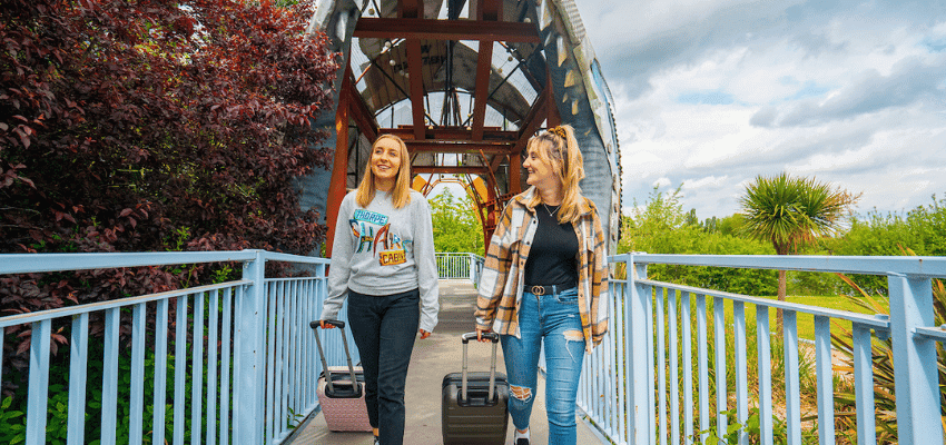 Two women with suitcases on a bridge at Thorpe Park, Purpl discounts for disabilities and long term health conditions, disabled travel discounts UK.