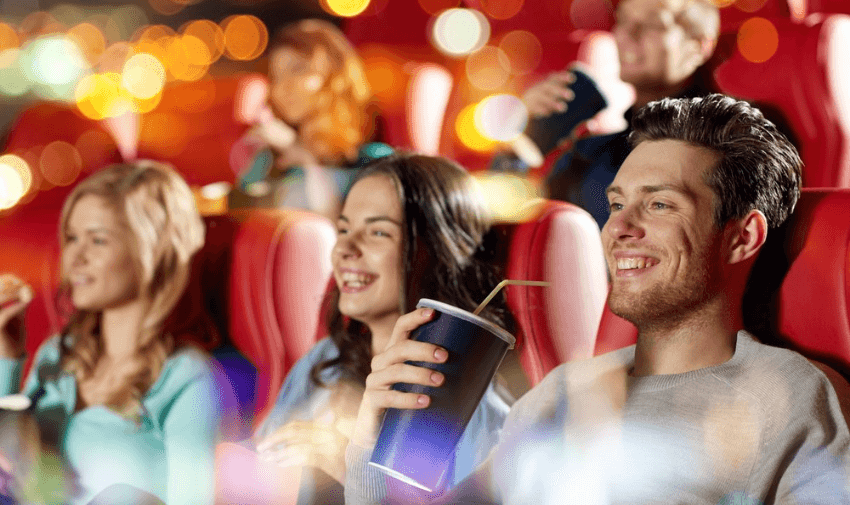 Group of friends enjoying drinks and watching a film in a brightly lit cinema, representing accessible entertainment and discounted Odeon tickets for disabled people and carers.
