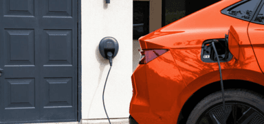 Orange electric car charging at home using a Pod Point EV charger. Accessible energy savings and mobility discounts for disabled drivers through Purpl.
