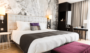 Modern hotel room with wide access, a plush bed and spacious layout. Holiday discounts for disabled travellers.