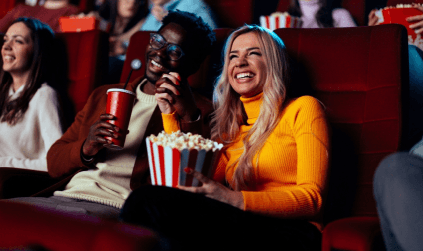 A couple enjoying popcorn and drinks while laughing at a film inside a Showcase cinema – ideal for promoting disability cinema discounts and accessible entertainment offers.