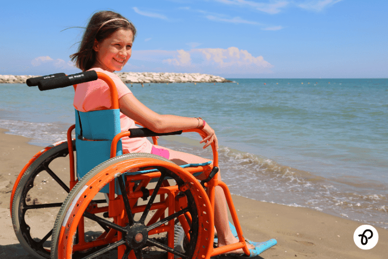 Child using a wheelchair enjoying an accessible beach holiday, representing disability holiday discounts, accessible travel breaks and inclusive holidays for people with disabilities and long-term health conditions in the UK.