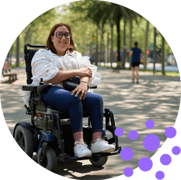 Woman using a powered wheelchair outdoors, showing independence and disability grants UK for mobility support and long term health conditions.