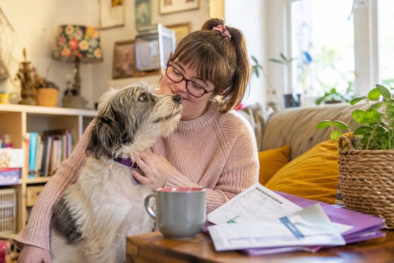 Disabled person sitting with their dog while reviewing vet bill paperwork at home