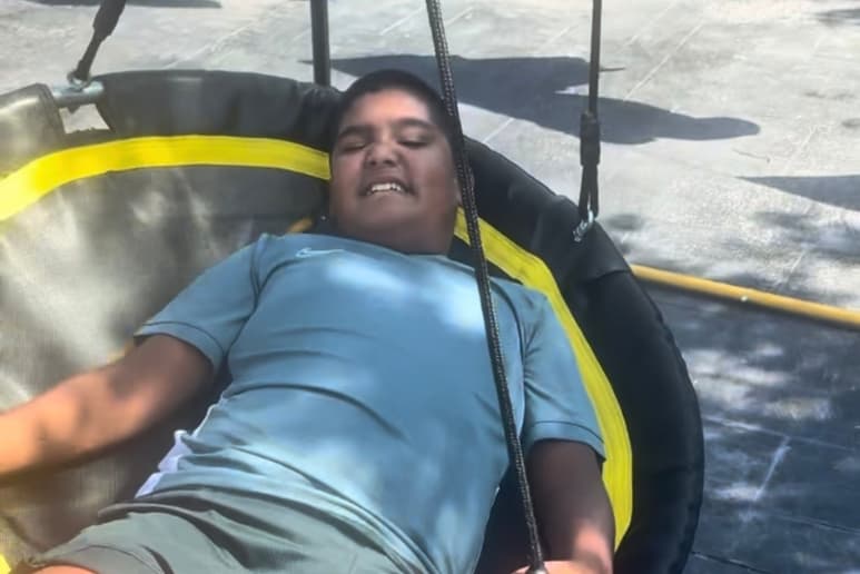 Qasim, an autistic child, relaxing on the sensory swing funded through the Purpl Community Grant Fund.